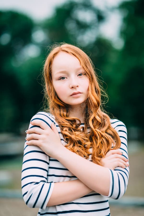 Ragazza dai capelli rossi adorabile che si abbraccia e che esamina macchina fotografica fotografia stock libera da diritti Ragazza dai capelli rossi adorabile che si abbraccia e che esamina macchina fotografica fotografia stock libera da diritti