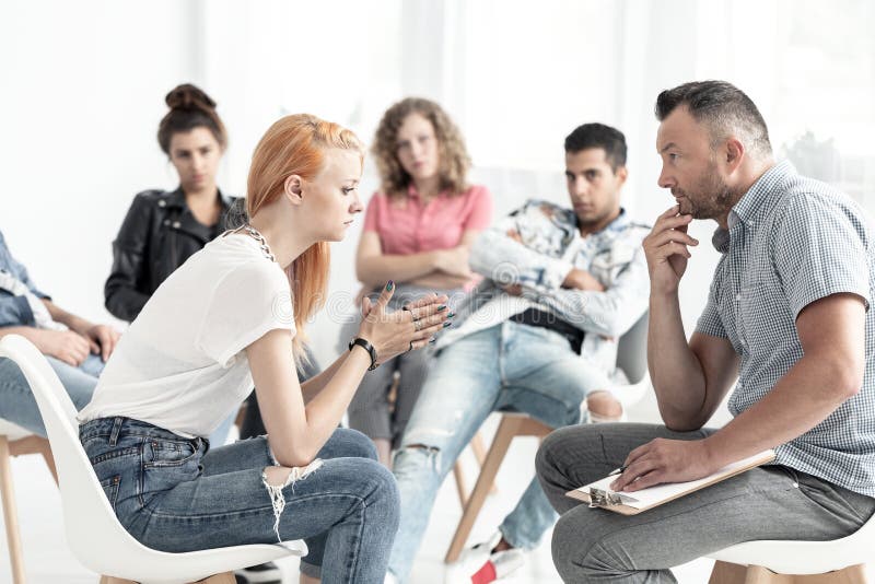 Ragazza dai capelli rossi ribelle che parla con consulente durante il meeti immagini stock Ragazza dai capelli rossi ribelle che parla con consulente durante il meeti immagini stock