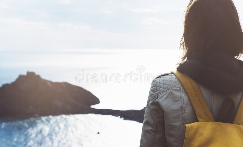 Ragazza dei pantaloni a vita bassa con lo zaino che gode del tramonto su vista sul mare sulla montagna di punta Il viaggiatore tu immagini stock Ragazza dei pantaloni a vita bassa con lo zaino che gode del tramonto su vista sul mare sulla montagna di punta Il viaggiatore tu immagini stock