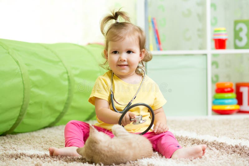 Ragazza del bambino che gioca al dottore With un gatto fotografia stock Ragazza del bambino che gioca al dottore With un gatto fotografia stock