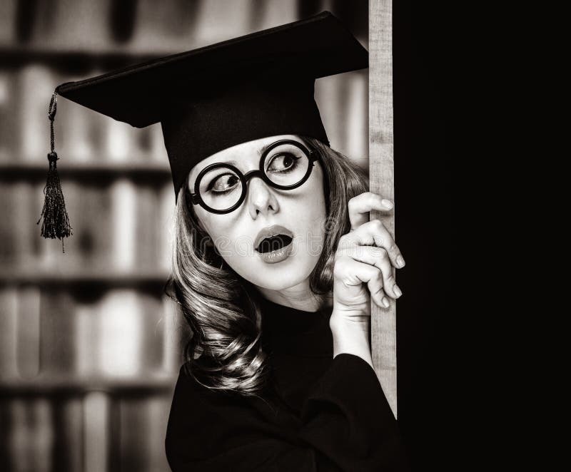 Ragazza dello studente di laurea in un abito accademico vicino alla lavagna fotografia stock Ragazza dello studente di laurea in un abito accademico vicino alla lavagna fotografia stock