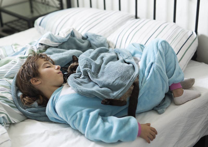 Ragazza di 10 anni che dorme a letto con il suo gatto sulla cima immagini stock libere da diritti Ragazza di 10 anni che dorme a letto con il suo gatto sulla cima immagini stock libere da diritti