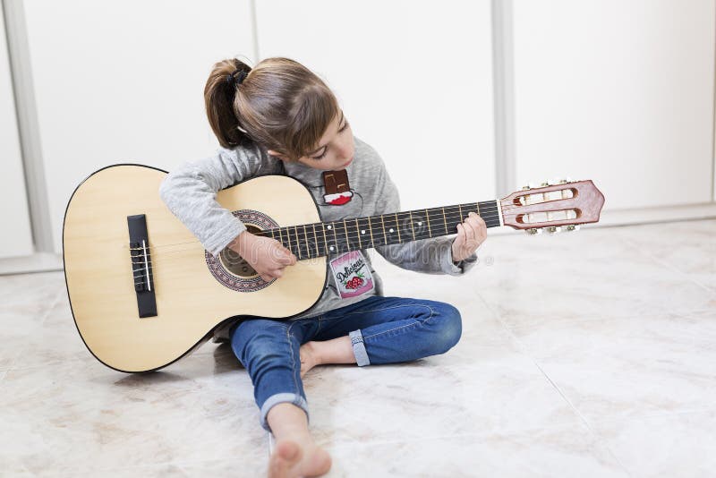 Ragazza di 9 anni che impara giocare la chitarra fotografia stock Ragazza di 9 anni che impara giocare la chitarra fotografia stock