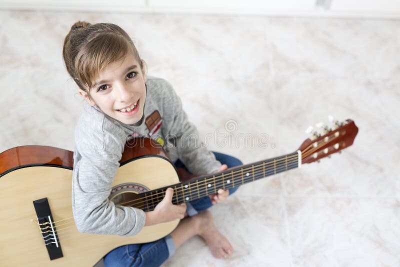 Ragazza di 9 anni che impara giocare la chitarra fotografie stock libere da diritti Ragazza di 9 anni che impara giocare la chitarra fotografie stock libere da diritti