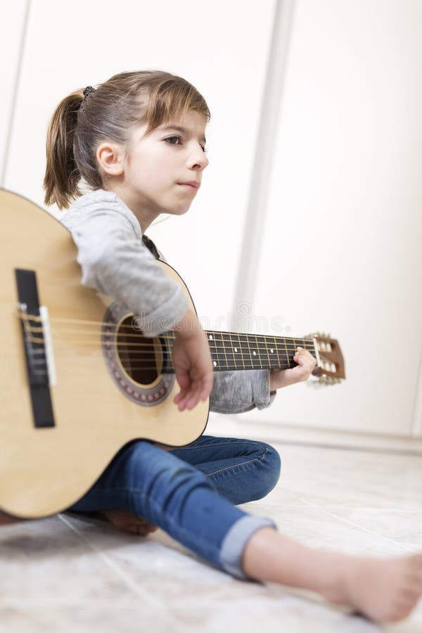 Ragazza di 9 anni che impara giocare la chitarra fotografie stock libere da diritti Ragazza di 9 anni che impara giocare la chitarra fotografie stock libere da diritti