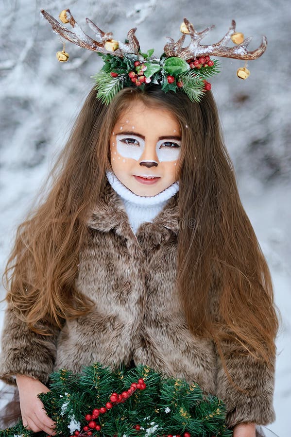 Ragazza di fiaba Ritratto che una bambina in un cervo si veste con un fronte dipinto corno marrone della foresta dell'inverno nel