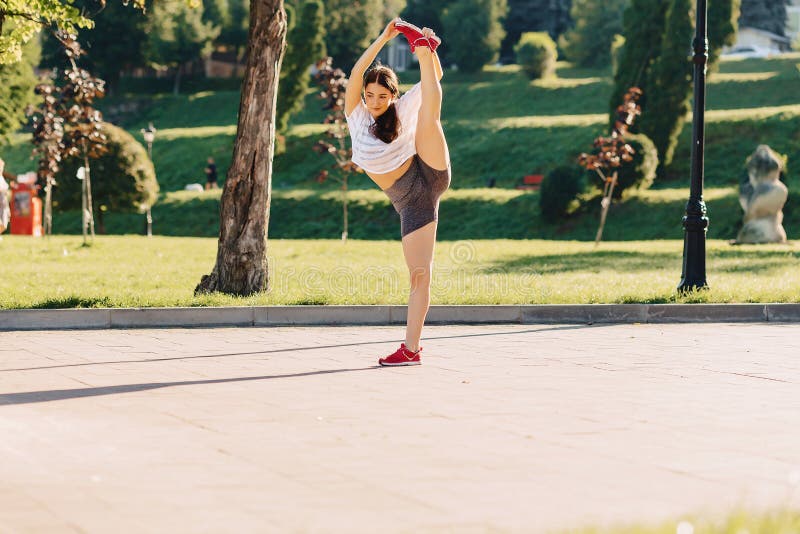 ragazza di forma fisica che fa allungamento al parco al sole di mattina fotografia stock ragazza di forma fisica che fa allungamento al parco al sole di mattina fotografia stock
