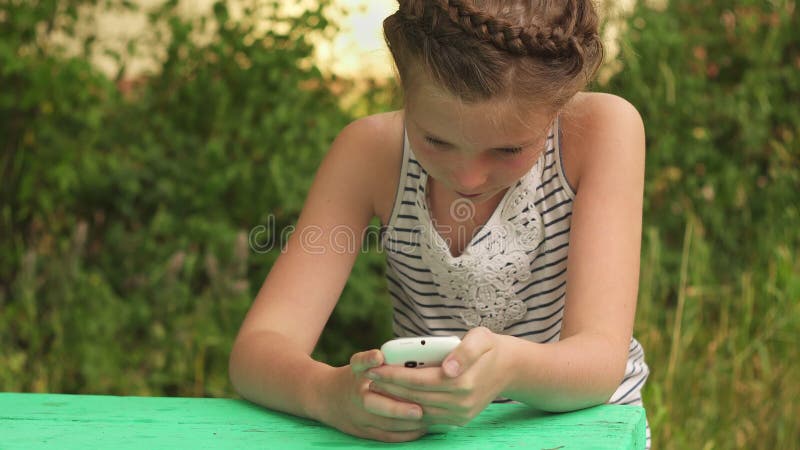 Ragazza di seduta Concerned che esamina smartphone sugli ambiti di provenienza della natura