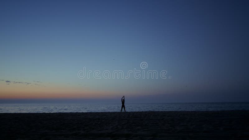 Ragazza di silhouette atleta che fa ginnastica in mare al crepuscolo. donna che pratica yoga. stock footage