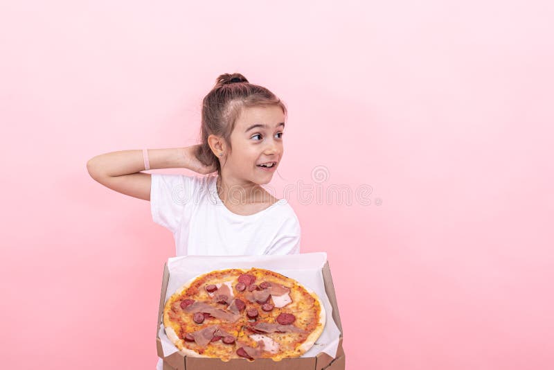 Ragazza divertente con la pizza in una scatola su uno sfondo rosa immagine stock