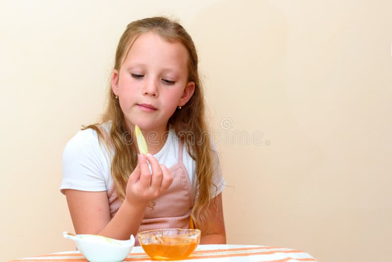 Ragazza ebrea che immerge le fette della mela nel miele su Rosh HaShanah immagine stock libera da diritti Ragazza ebrea che immerge le fette della mela nel miele su Rosh HaShanah immagine stock libera da diritti