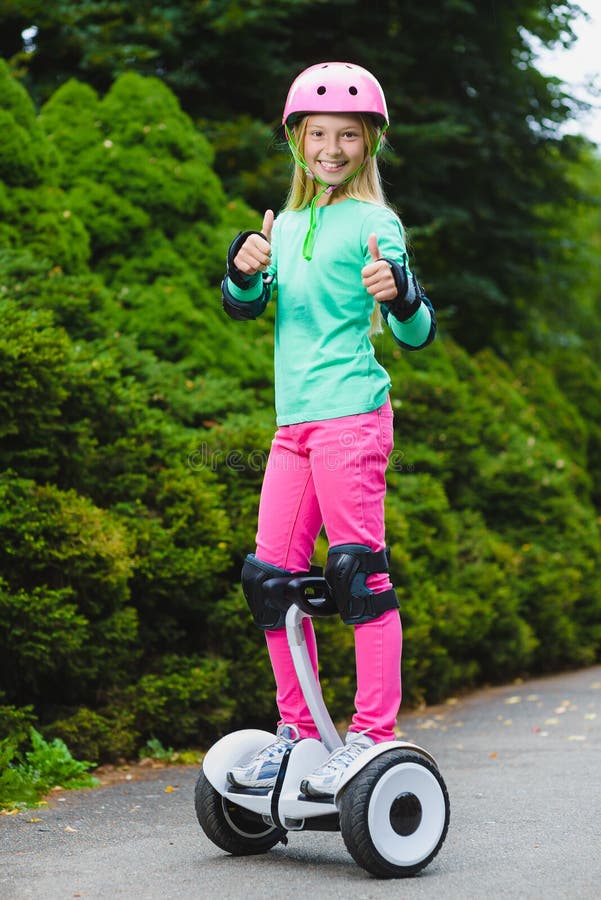 Ragazza felice che sta sul hoverboard o gyroscooter all'aperto immagine stock Ragazza felice che sta sul hoverboard o gyroscooter all'aperto immagine stock