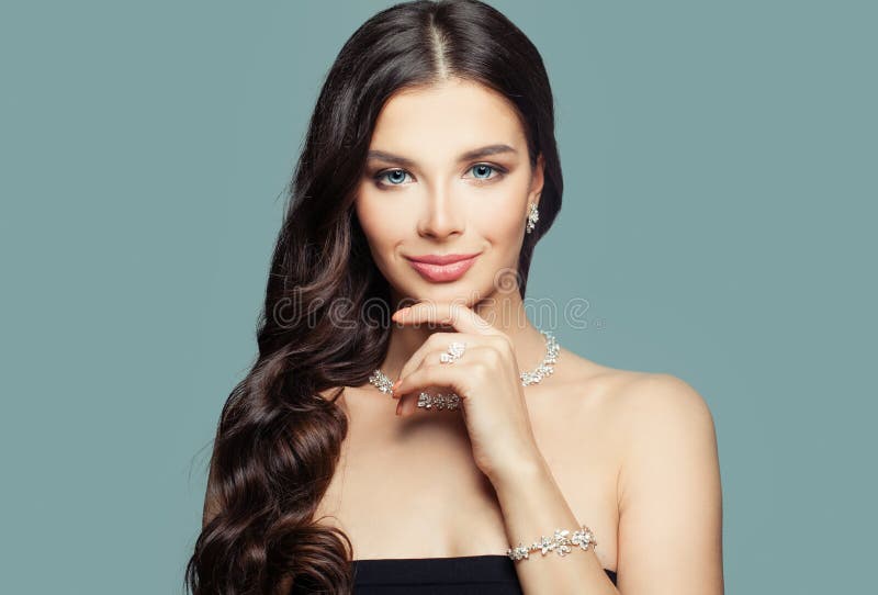 Ragazza felice con gioielli Donna castana con trucco e collana riccia di diamante e dell'acconciatura su fondo blu immagine stock libera da diritti Ragazza felice con gioielli Donna castana con trucco e collana riccia di diamante e dell'acconciatura su fondo blu immagine stock libera da diritti