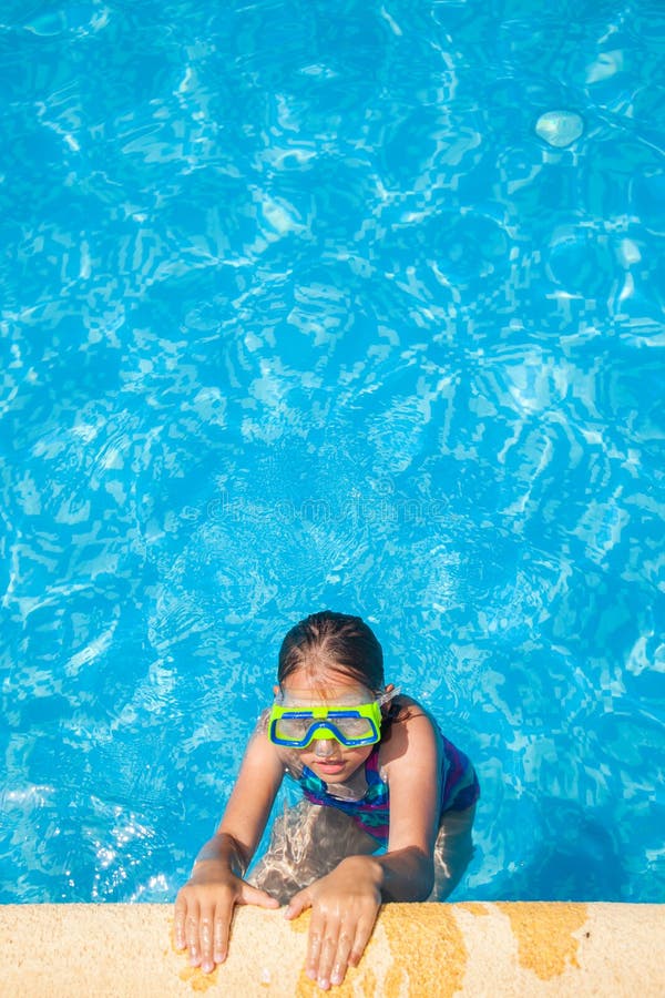 Ragazza felice con gli occhiali di protezione nella piscina fotografia stock Ragazza felice con gli occhiali di protezione nella piscina fotografia stock