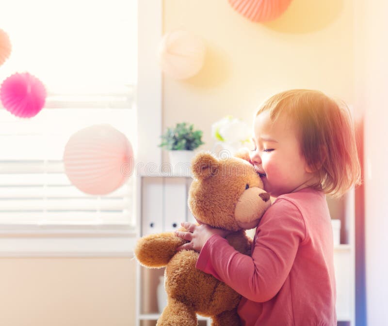 Ragazza felice del bambino che gioca con il suo orsacchiotto fotografia stock libera da diritti Ragazza felice del bambino che gioca con il suo orsacchiotto fotografia stock libera da diritti