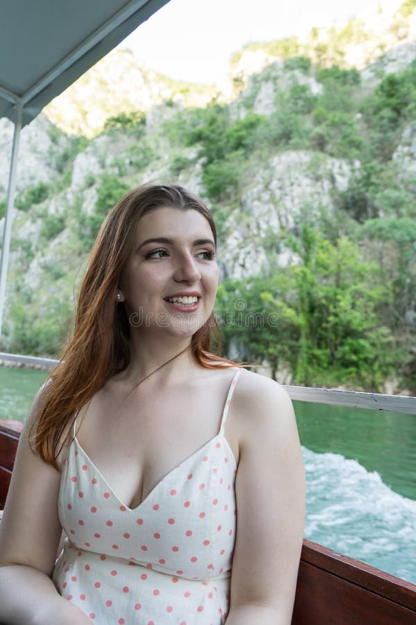 Ragazza felice in una piccola barca che sorride con i vestiti di estate Testa rossa della donna bianca turistica della pelle in u immagine stock Ragazza felice in una piccola barca che sorride con i vestiti di estate Testa rossa della donna bianca turistica della pelle in u immagine stock