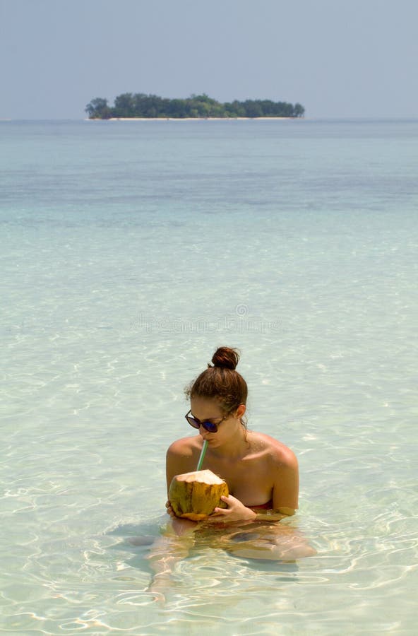 Ragazza graziosa con gli occhiali da sole che beve noce di cocco fresca fotografia stock libera da diritti Ragazza graziosa con gli occhiali da sole che beve noce di cocco fresca fotografia stock libera da diritti
