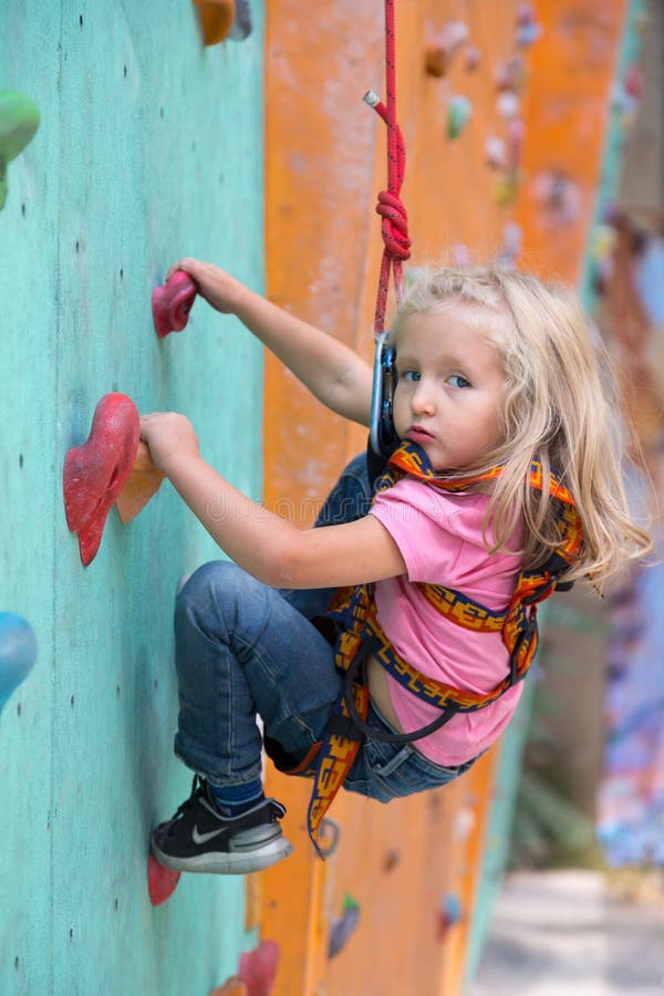 Ragazza infantile che fa i primi punti sulla parete rampicante fotografie stock libere da diritti Ragazza infantile che fa i primi punti sulla parete rampicante fotografie stock libere da diritti