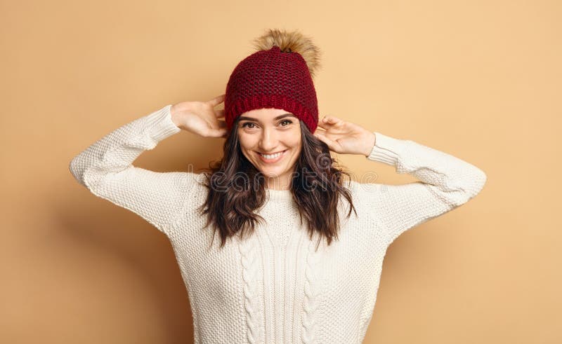Ragazza in maglione ed in Beanie Hat tricottati sopra fondo beige fotografie stock Ragazza in maglione ed in Beanie Hat tricottati sopra fondo beige fotografie stock
