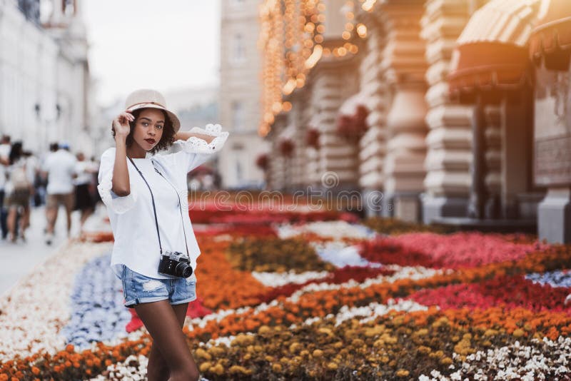 Ragazza nera con la retro camma sulla via vicino all'aiola fotografia stock libera da diritti Ragazza nera con la retro camma sulla via vicino all'aiola fotografia stock libera da diritti
