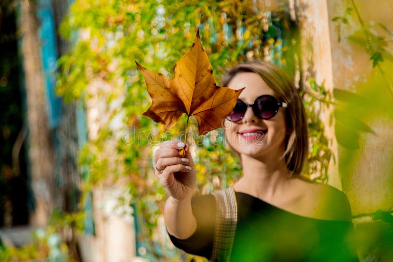 Ragazza in occhiali da sole che tengono una foglia fotografie stock libere da diritti Ragazza in occhiali da sole che tengono una foglia fotografie stock libere da diritti