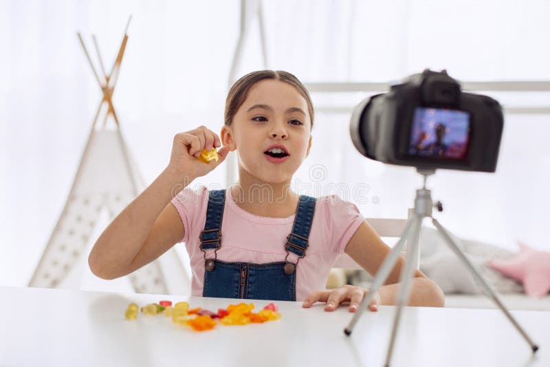 Ragazza ottimistica che parla del gusto delle caramelle gommose nel vlog fotografia stock libera da diritti Ragazza ottimistica che parla del gusto delle caramelle gommose nel vlog fotografia stock libera da diritti