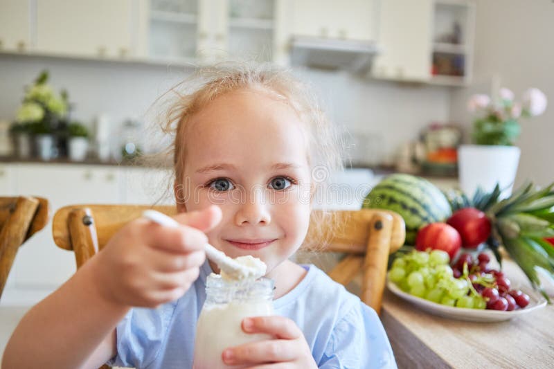 Ragazza sorridente che mangia parfait con cucchiaio a casa immagini stock
