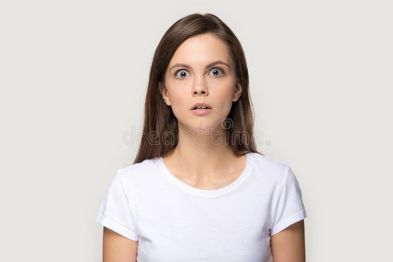 Ragazza spaventata che esamina macchina fotografica che posa sopra il fondo grigio dello studio immagine stock Ragazza spaventata che esamina macchina fotografica che posa sopra il fondo grigio dello studio immagine stock