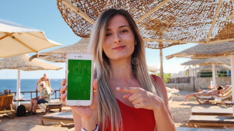 Ragazza sulla manifestazione di vacanza lo smartphone verde dello schermo all'aperto Mano alta vicina della donna che tiene e che