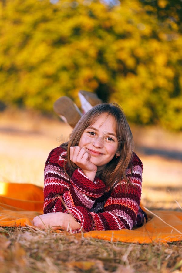Ragazza sveglia in autunno, situantesi all'aperto immagine stock Ragazza sveglia in autunno, situantesi all'aperto immagine stock