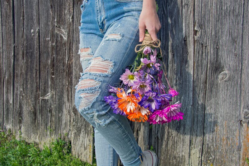 Ragazza teenager con i jeans e le margherite sfilacciati immagini stock Ragazza teenager con i jeans e le margherite sfilacciati immagini stock