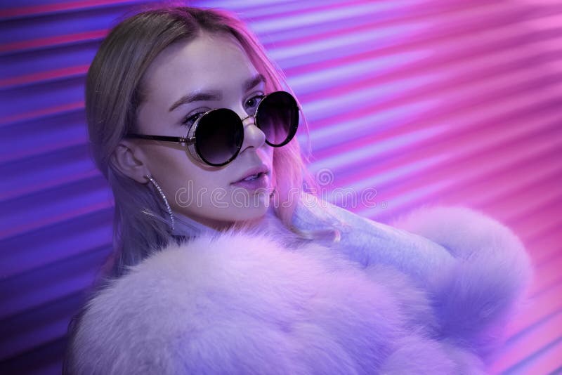 Ragazza teenager dei pantaloni a vita bassa in pelliccia alla moda di vetro che posa sul fondo leggero al neon della via fotografia stock libera da diritti Ragazza teenager dei pantaloni a vita bassa in pelliccia alla moda di vetro che posa sul fondo leggero al neon della via fotografia stock libera da diritti
