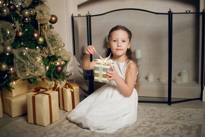Ragazza in vestito che si siede vicino all'albero di Natale e che tiene i regali fotografia stock libera da diritti Ragazza in vestito che si siede vicino all'albero di Natale e che tiene i regali fotografia stock libera da diritti