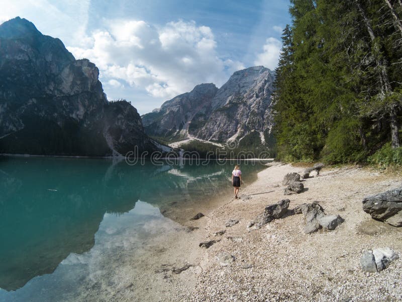 Ragazze che camminano contro la vista stupefacente del lago Braies Lago di Braies con la foresta dell'estate e montagne ha rifles fotografia stock Ragazze che camminano contro la vista stupefacente del lago Braies Lago di Braies con la foresta dell'estate e montagne ha rifles fotografia stock