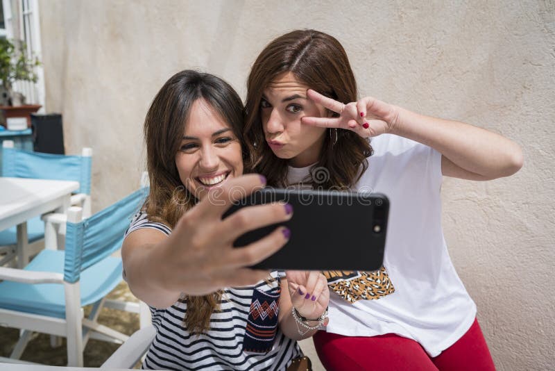 2 ragazze che fanno un selfie su un terrazzo immagini stock 2 ragazze che fanno un selfie su un terrazzo immagini stock