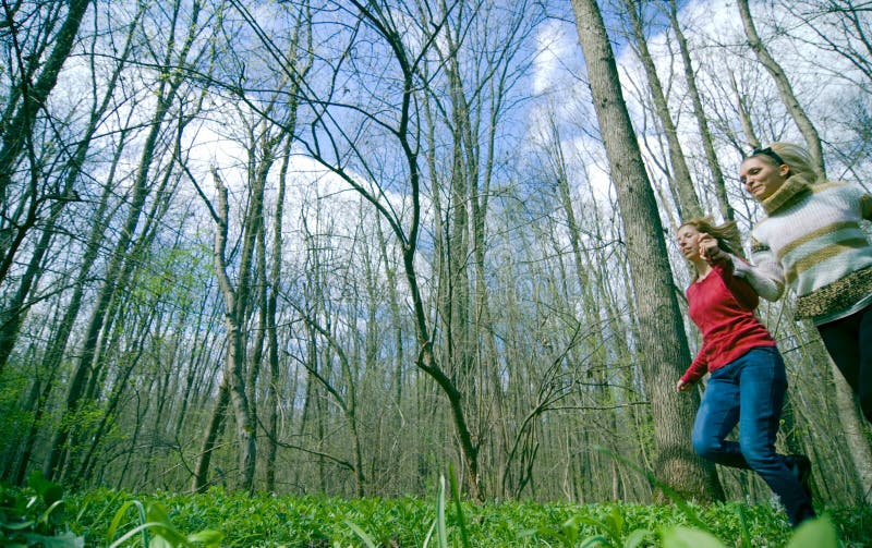 Ragazze che funzionano attraverso una foresta immagini stock Ragazze che funzionano attraverso una foresta immagini stock