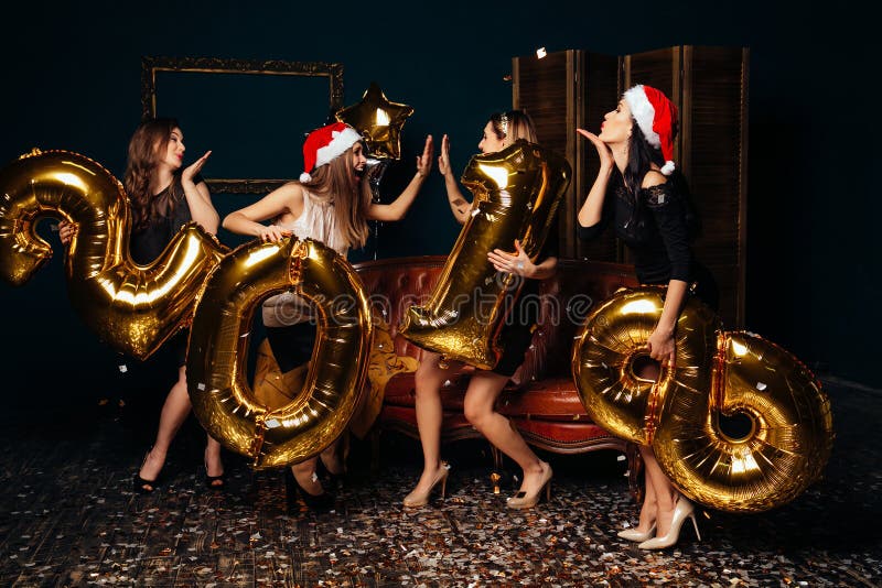 Group of beautiful young girls in Santa hats dancing and looking happy at New year party. Group of beautiful young girls in Santa hats dancing and looking happy at New year party