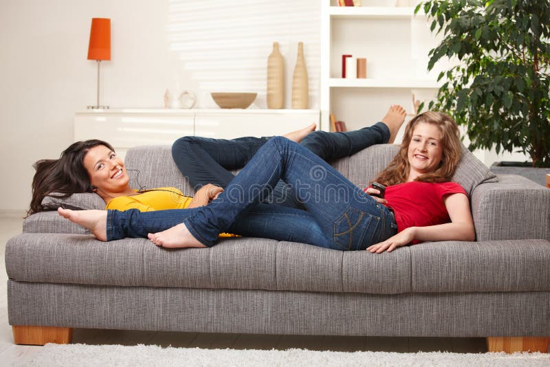 Ragazze teenager felici che sorridono sul sofà immagine stock Ragazze teenager felici che sorridono sul sofà immagine stock