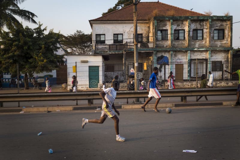 Ragazzi che giocano a calcio in una strada della città di Bissau fotografia stock Ragazzi che giocano a calcio in una strada della città di Bissau fotografia stock