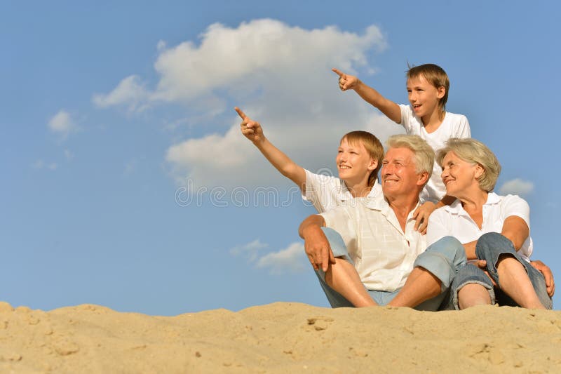 Ragazzi con i nonni che si siedono sulla sabbia fotografia stock Ragazzi con i nonni che si siedono sulla sabbia fotografia stock