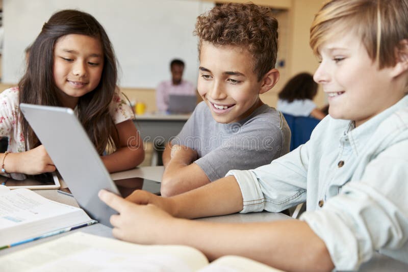 Ragazzi della scuola elementare che utilizzano il computer della compressa nella classe di scuola fotografia stock Ragazzi della scuola elementare che utilizzano il computer della compressa nella classe di scuola fotografia stock