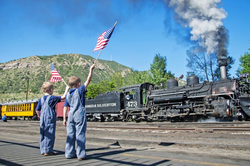 Ragazzi nella partenza del treno della bandiera americana dell'onda dei camici immagine stock Ragazzi nella partenza del treno della bandiera americana dell'onda dei camici immagine stock