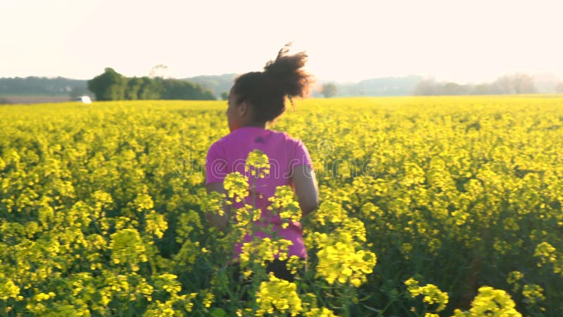 Ragazzina afro-americana adolescente, giovane donna che corre o fa jogging nel campo dei fiori gialli