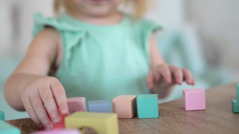 Ragazzina irriconoscibile che gioca con cubi di legno colorati stock footage
