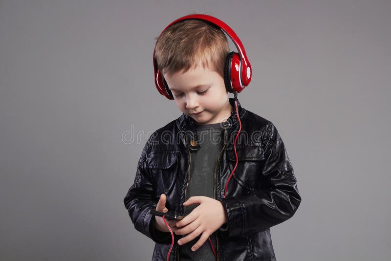 Ragazzino alla moda in cuffie musica d'ascolto del bambino bello immagine stock Ragazzino alla moda in cuffie musica d'ascolto del bambino bello immagine stock