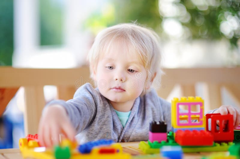 Un bambino piccolo che gioca con blocchi di plastica colorati all'asilo nido immagine stock
