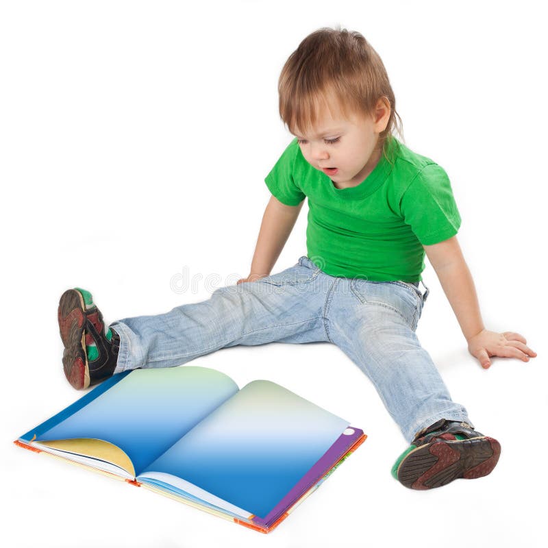 Ragazzino con un libro che si siede sul pavimento fotografia stock libera da diritti Ragazzino con un libro che si siede sul pavimento fotografia stock libera da diritti