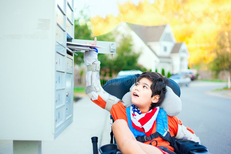 Disabled ten year old boy in wheelchair reaching up to get mail from mailbox outdoors. Disabled ten year old boy in wheelchair reaching up to get mail from mailbox outdoors