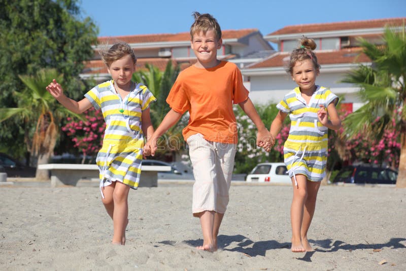 Ragazzino e due ragazze che camminano sulla spiaggia fotografia stock libera da diritti Ragazzino e due ragazze che camminano sulla spiaggia fotografia stock libera da diritti