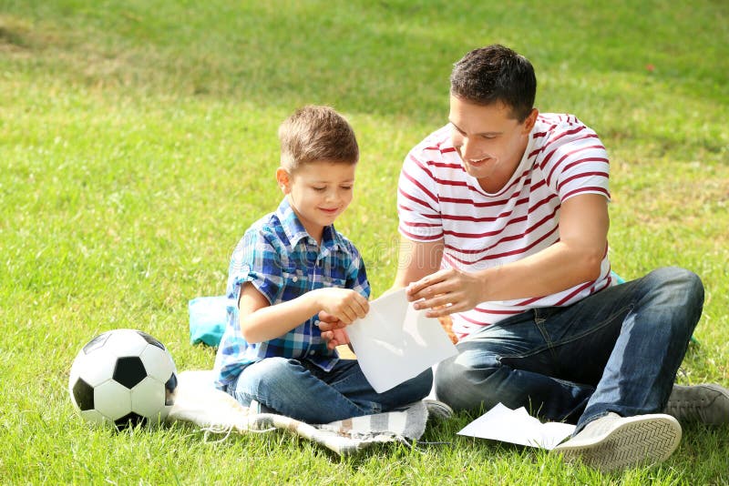Ragazzino ed suo padre che fanno per incartare aereo all'aperto immagine stock libera da diritti Ragazzino ed suo padre che fanno per incartare aereo all'aperto immagine stock libera da diritti